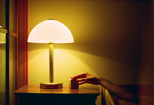 Hand on alarm next to bed lamp