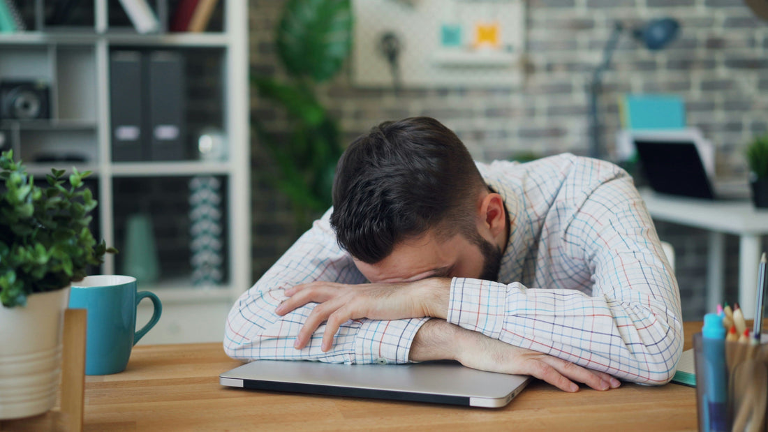 man falling asleep on arms on desk